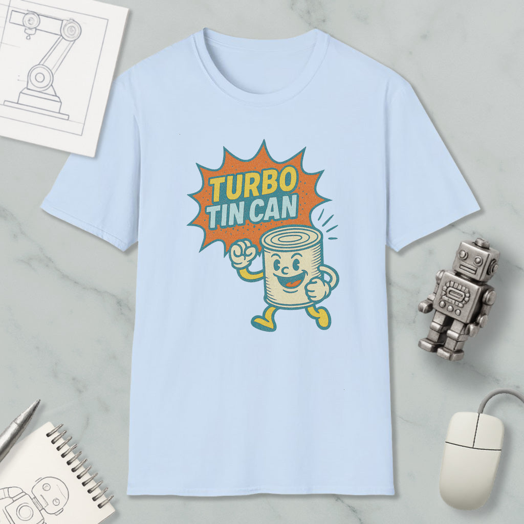 a light blue t-shirt with a graphic design depicting a tin can character with a speech bubble saying "TURBO TIN CAN". The t-shirt is placed on a marble surface, surrounded by various objects such as a computer mouse, a notebook, and a small robot figurine.