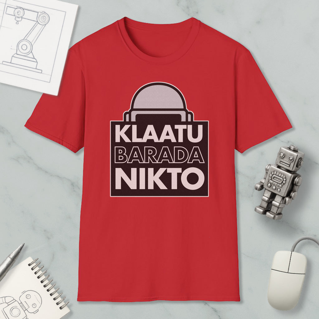 a red t-shirt with a graphic design, a computer mouse, a notebook, and a small robot figurine.