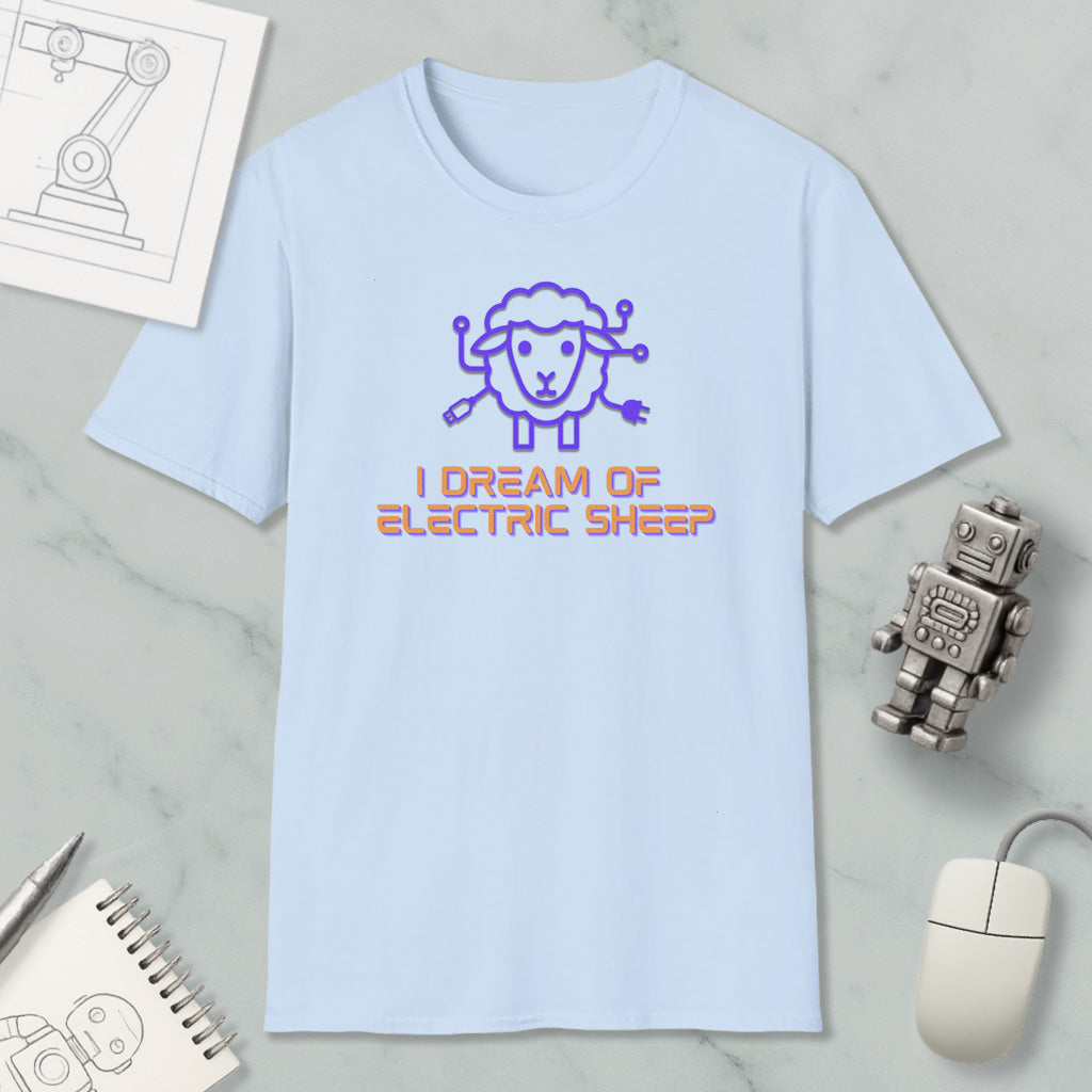 a light blue t-shirt with a cartoon sheep design and the text "I DREAM OF ELECTRIC SHEEP?" printed on it. The t-shirt is placed on a marble surface, along with a computer mouse, a pen, and a notebook.