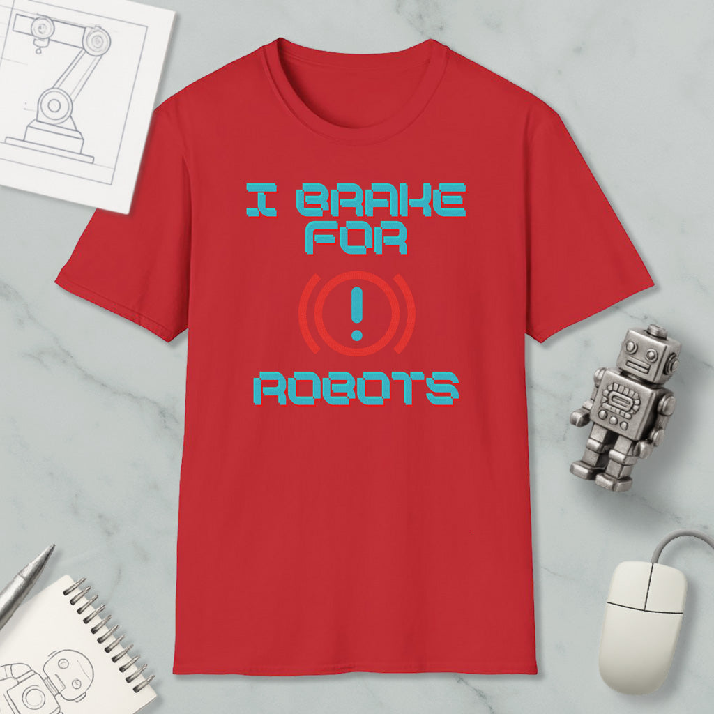 a red t-shirt with the text "I BRACE FOR ROBOTS" printed on it, along with a red exclamation mark symbol. The t-shirt is displayed on a marble surface, surrounded by various objects such as a computer mouse, a robot toy, and a piece of paper with a drawing of a robot.