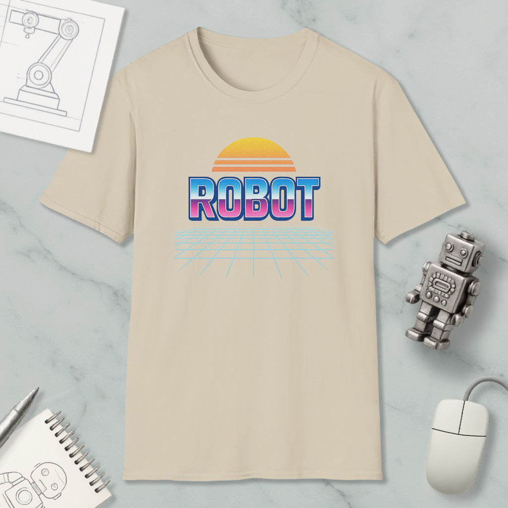 a beige t-shirt with a graphic design of a robot and a sunset, along with various objects such as a computer mouse, a notebook, and a toy robot.