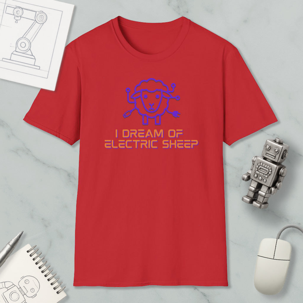 a red t-shirt with a blue sheep graphic and text, along with a computer mouse, a notebook, and a robot figurine, all placed on a marble surface.