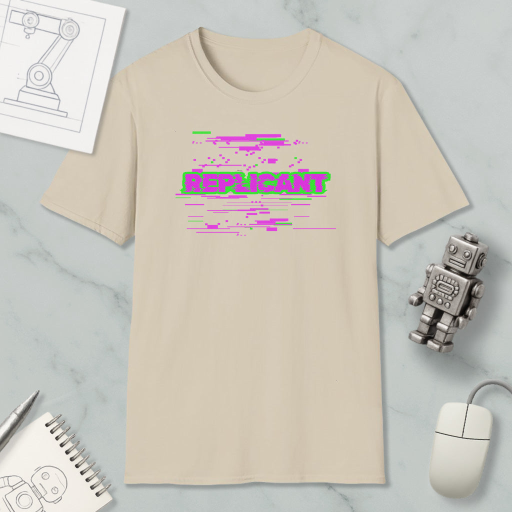 a beige t-shirt with a graphic design, a computer mouse, a notebook, and a small robot on a marble surface.