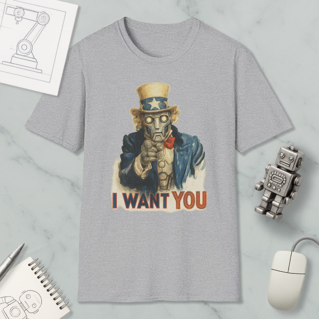 a gray t-shirt with a graphic design of a robot character and the text "I WANT YOU" printed on it. The t-shirt is placed on a marble surface, surrounded by various objects such as a computer mouse, a pen, a notebook, and a robot figurine.