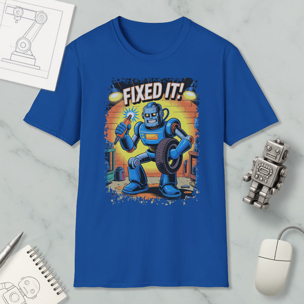 a blue t-shirt with a cartoon robot holding a wrench and the text "FIXED IT!" printed on it. The t-shirt is displayed on a marble surface, along with a computer mouse, a notepad, and a small robot figurine.