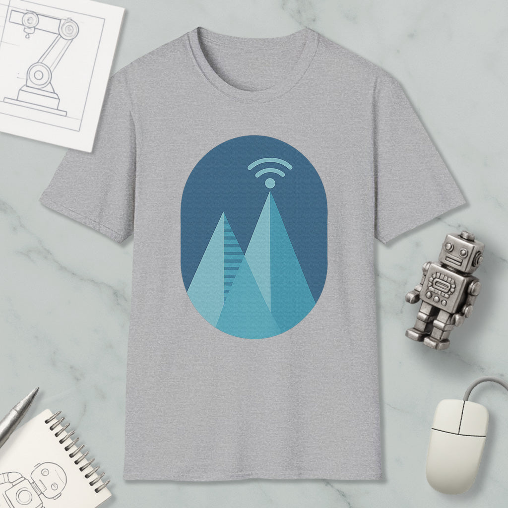 a gray t-shirt with a graphic design of a mountain range, a Wi-Fi symbol, and a robot figure. The t-shirt is placed on a marble surface, surrounded by various objects such as a notebook, a mouse, and a pen.
