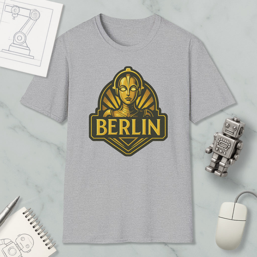 a gray t-shirt with a graphic design of a robot or character, along with a computer mouse, a notebook, and a pen on a marble surface.