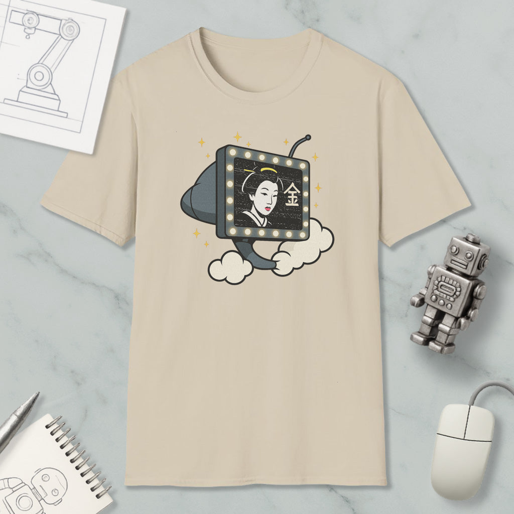 a beige t-shirt with a graphic design depicting a woman's face on a television screen, surrounded by clouds and stars. The t-shirt is placed on a marble surface, along with a computer mouse, a notebook, and a small robot figurine.