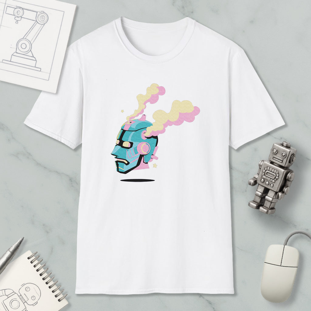 a white t-shirt with a colorful graphic design, including a robot or robot-like figure with a face and smoke coming out of its head. The t-shirt is placed on a marble surface, along with a computer mouse, a notepad, and a small robot figurine.