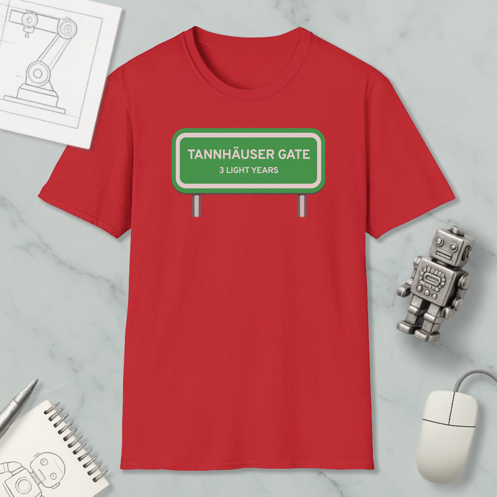 a red t-shirt with a green road sign that reads "Tannhäuser Gate" and "3 light years" printed on it. The t-shirt is placed on a marble surface, along with a computer mouse, a pen, and a notebook.