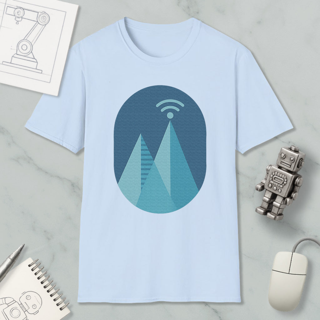a light blue t-shirt with a graphic design of a mountain range, a Wi-Fi symbol, and a robot figure. The t-shirt is placed on a marble surface, surrounded by various objects such as a notebook, a mouse, and a robot figure.