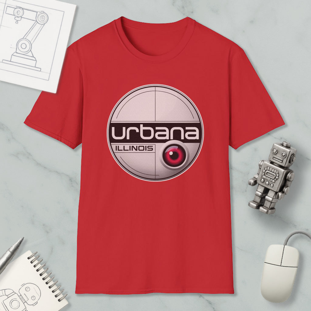 a red t-shirt with a graphic design, a computer mouse, a notebook, and a small robot on a marble surface.