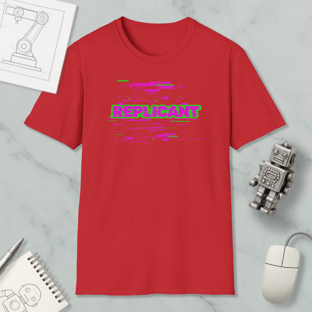 a red t-shirt with a graphic design, a computer mouse, a notebook, and a robot figurine on a marble surface.