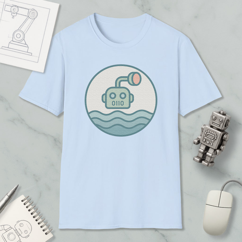 a light blue t-shirt with a circular graphic design depicting a robot or submarine, surrounded by a wave-like pattern. The t-shirt is placed on a marble surface, along with a computer mouse, a notepad, and a small robot figurine.
