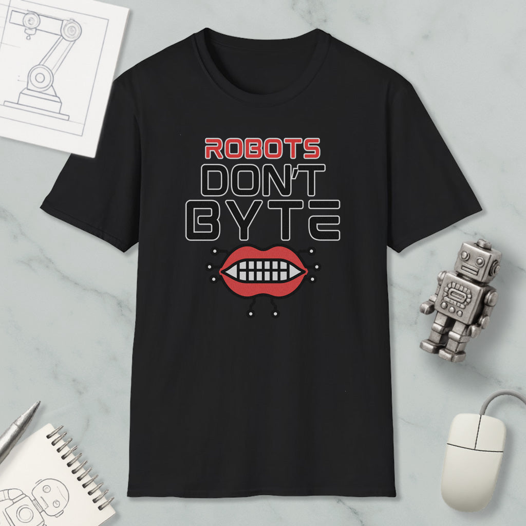 a black t-shirt with a graphic design that says "ROBOTS DON'T BYTE" and includes a graphic of a robot's mouth with teeth. The t-shirt is placed on a marble surface, along with a computer mouse, a notepad, and a small robot figurine.