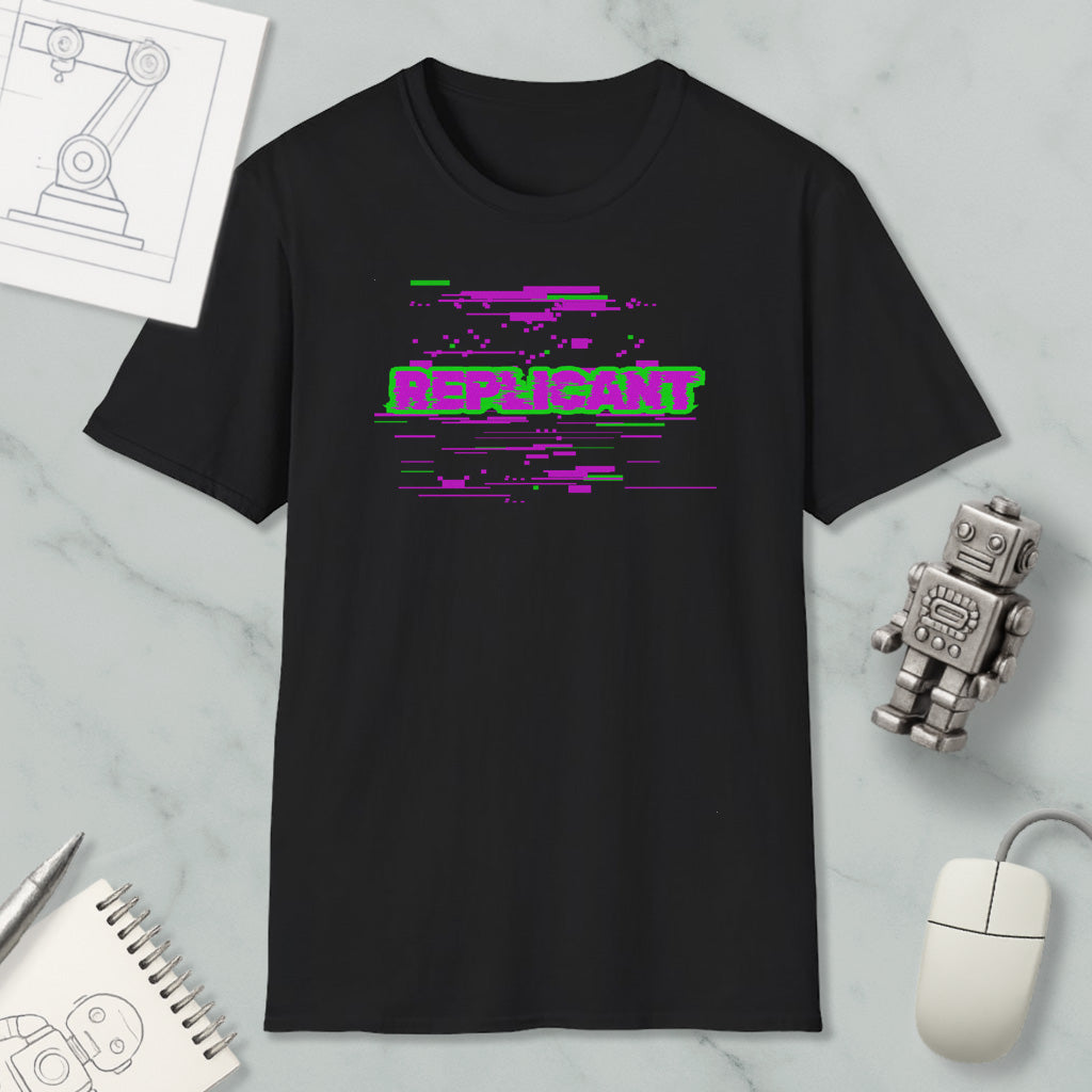 a black t-shirt with a graphic design, a computer mouse, a notebook, and a small robot figure on a marble surface.