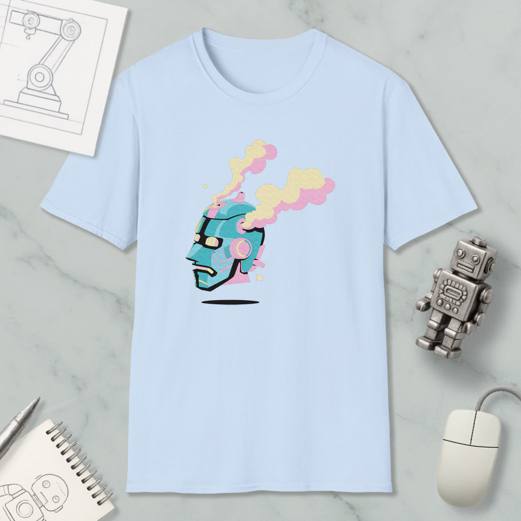 a light blue t-shirt with a colorful graphic design, including a robot or robot-like figure with a face and smoke coming out of its head. The t-shirt is placed on a marble surface, along with a computer mouse, a spiral notebook, and a small robot figurine.