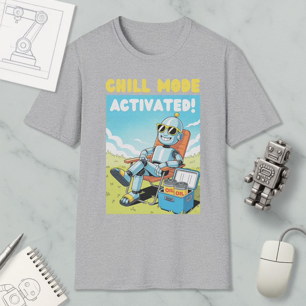 a gray t-shirt with a cartoon robot sitting in a chair and holding a cooler, with the text "Chill mode activated!" printed on it. The t-shirt is surrounded by various objects, including a computer mouse, a pen, a notebook, and a small robot figurine.