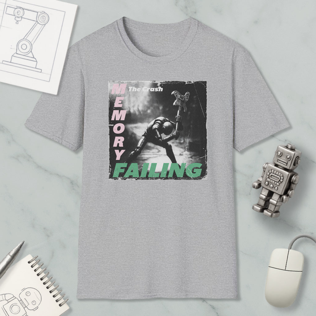 a grey t-shirt with a graphic design depicting a person in a robot-like pose, along with the text "The crash memory failing". The t-shirt is displayed on a marble surface, accompanied by various objects such as a computer mouse, a notebook, and a robot figurine.