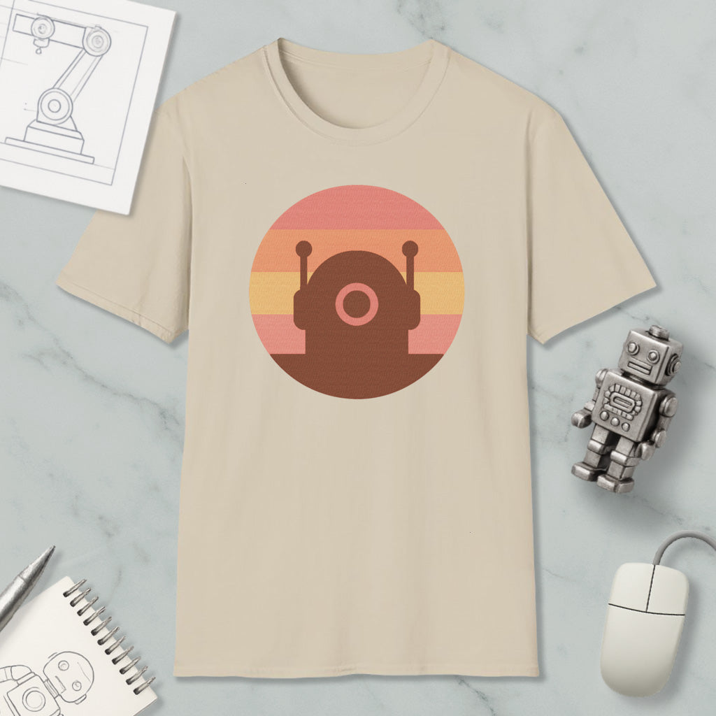 a beige t-shirt with a circular graphic design, a small robot, a computer mouse, and a notebook on a marble surface.