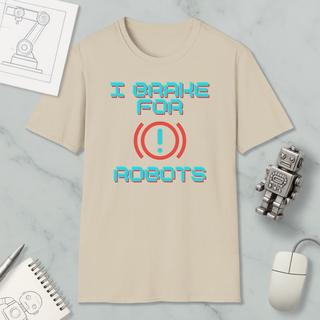 a beige t-shirt with the text "I brake for robots" printed on it, along with a red exclamation mark symbol. The t-shirt is placed on a marble surface, and there are various objects such as a computer mouse, a robot toy, and a notebook nearby.