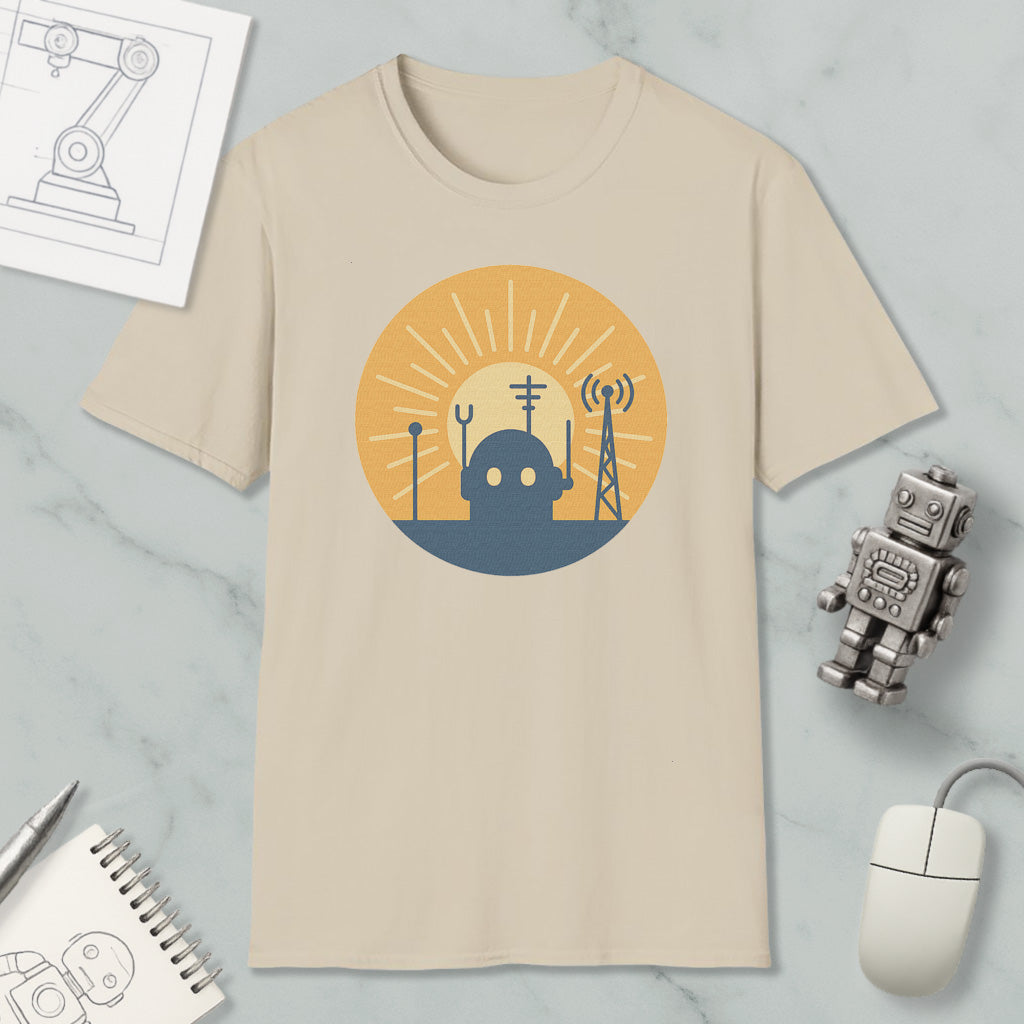 a beige t-shirt with a graphic design depicting a robot and various technological elements, such as a tower and antenna, set against a sun-like background. The t-shirt is displayed on a marble surface, along with a small robot figurine and a computer mouse.