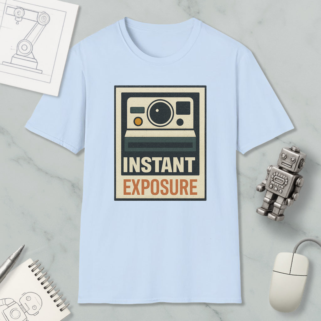 a light blue t-shirt with a graphic design of a camera and the text "INSTANT EXPOSURE" printed on it, along with a small robot toy and a computer mouse.