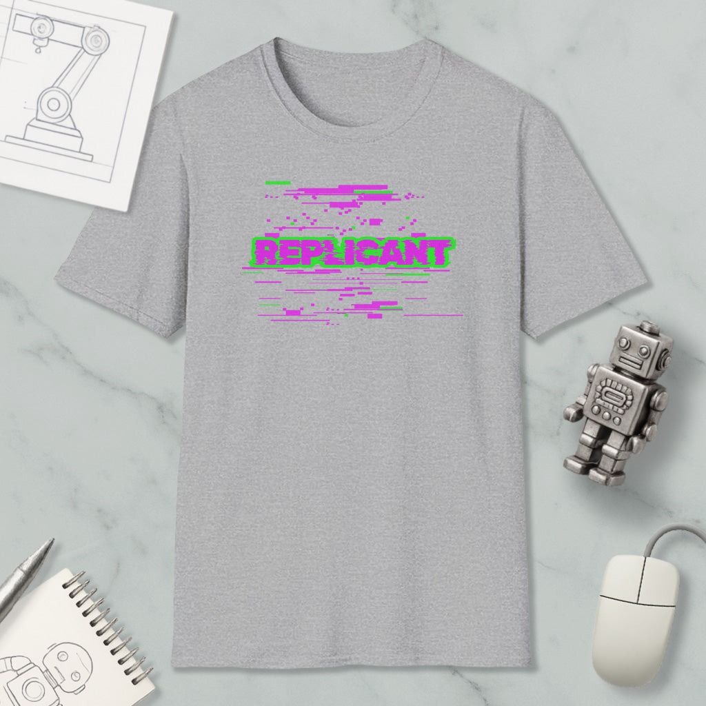 a gray t-shirt with a graphic design, a computer mouse, a notebook, and a small robot on a marble surface.