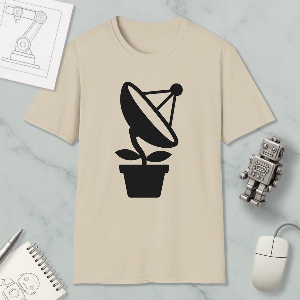 a beige t-shirt with a black satellite dish graphic, a small robot, a mouse, and a notebook on a marble surface.