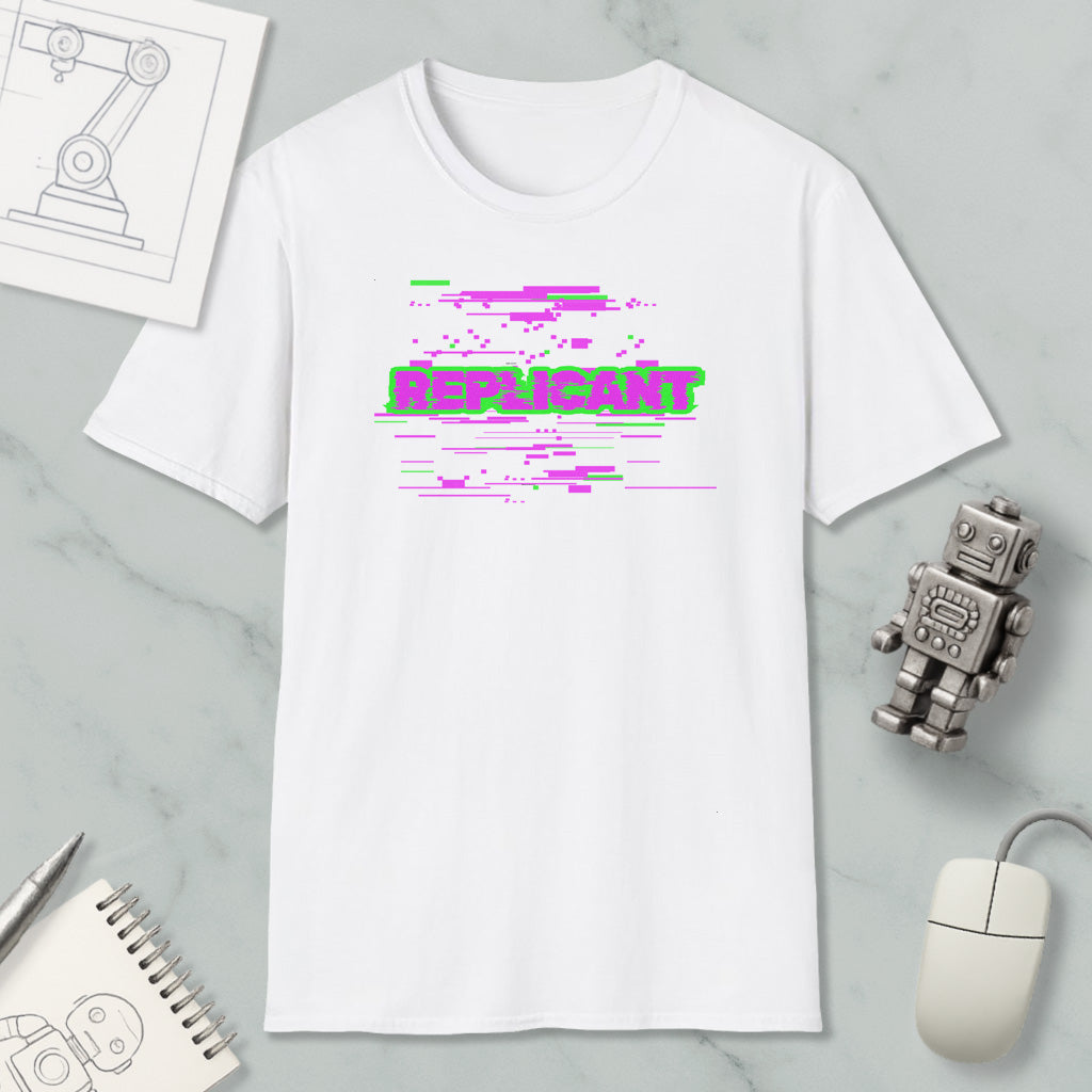 a white t-shirt with a graphic design, a computer mouse, a notebook, and a small robot on a marble surface.