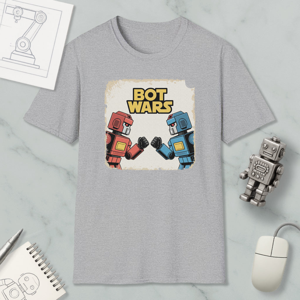 a gray t-shirt with a graphic design of two robot characters, one in red and one in blue, facing each other and appearing to engage in a battle. The t-shirt is surrounded by various objects, including a computer mouse, a pen, a notebook, and a small robot figurine.