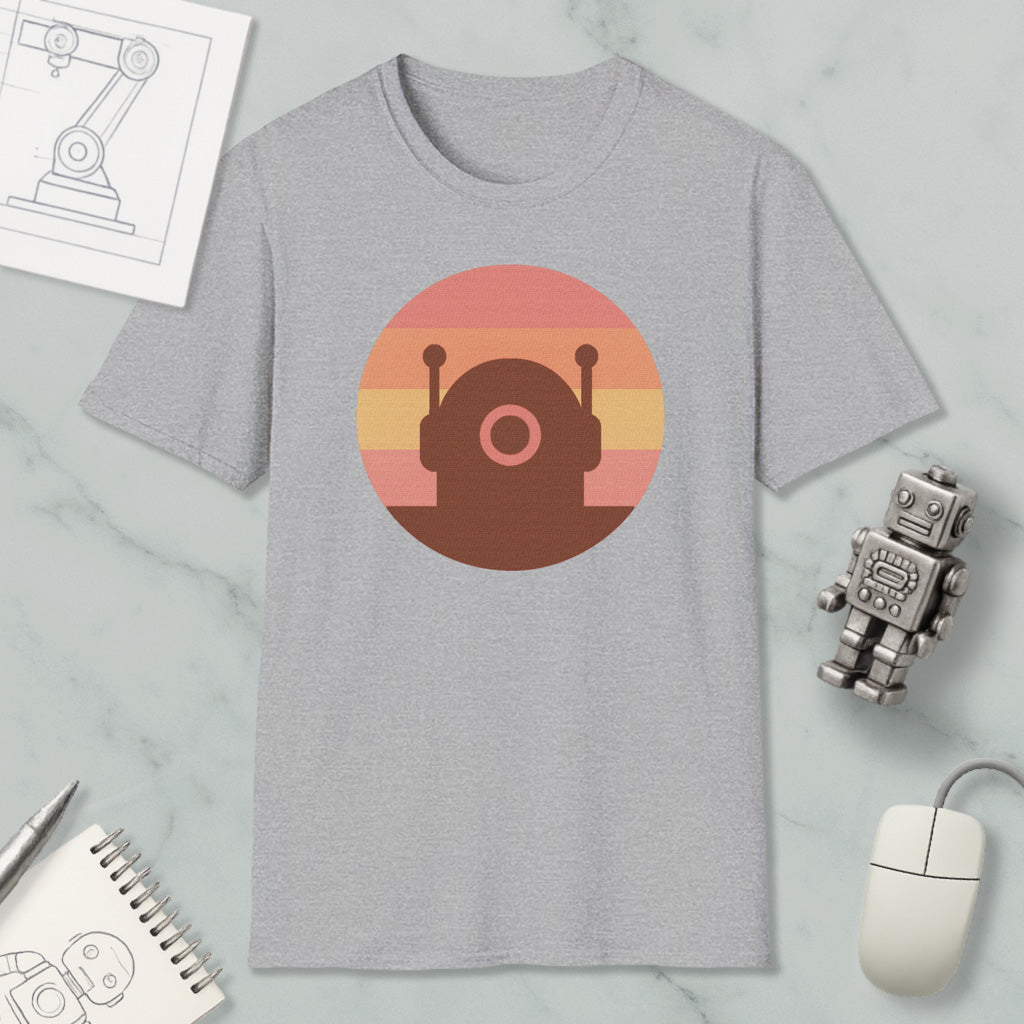 a gray t-shirt with a circular graphic design, a small robot, a computer mouse, and a notebook on a marble surface.
