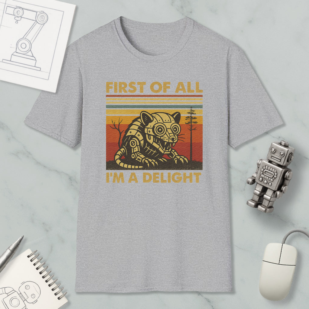 a gray t-shirt with a graphic design of a robot and the text "FIRST OF ALL I'M A DELIGHT" printed on it. The t-shirt is placed on a marble surface, along with a computer mouse, a notepad, and a small robot figurine.