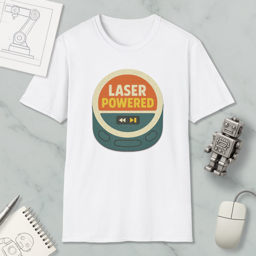 a white t-shirt with a graphic design that says "LASER POWERED" in bold letters. The t-shirt is placed on a marble surface, surrounded by various objects such as a computer mouse, a pen, a notebook, and a small robot.