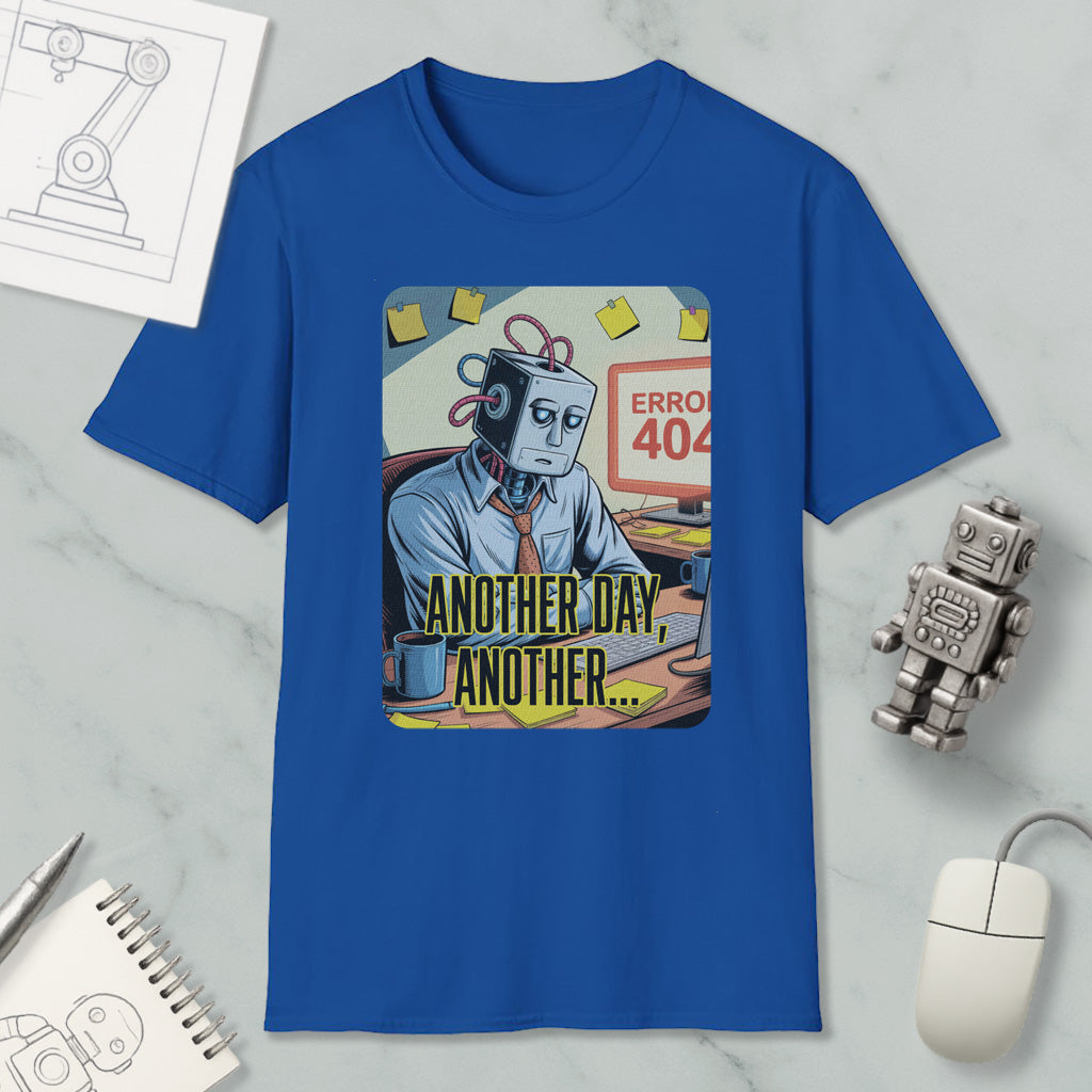 a blue t-shirt with a graphic design depicting a robot or robot-like figure sitting at a desk with a computer, surrounded by various objects such as a mouse, a keyboard, and a notepad.