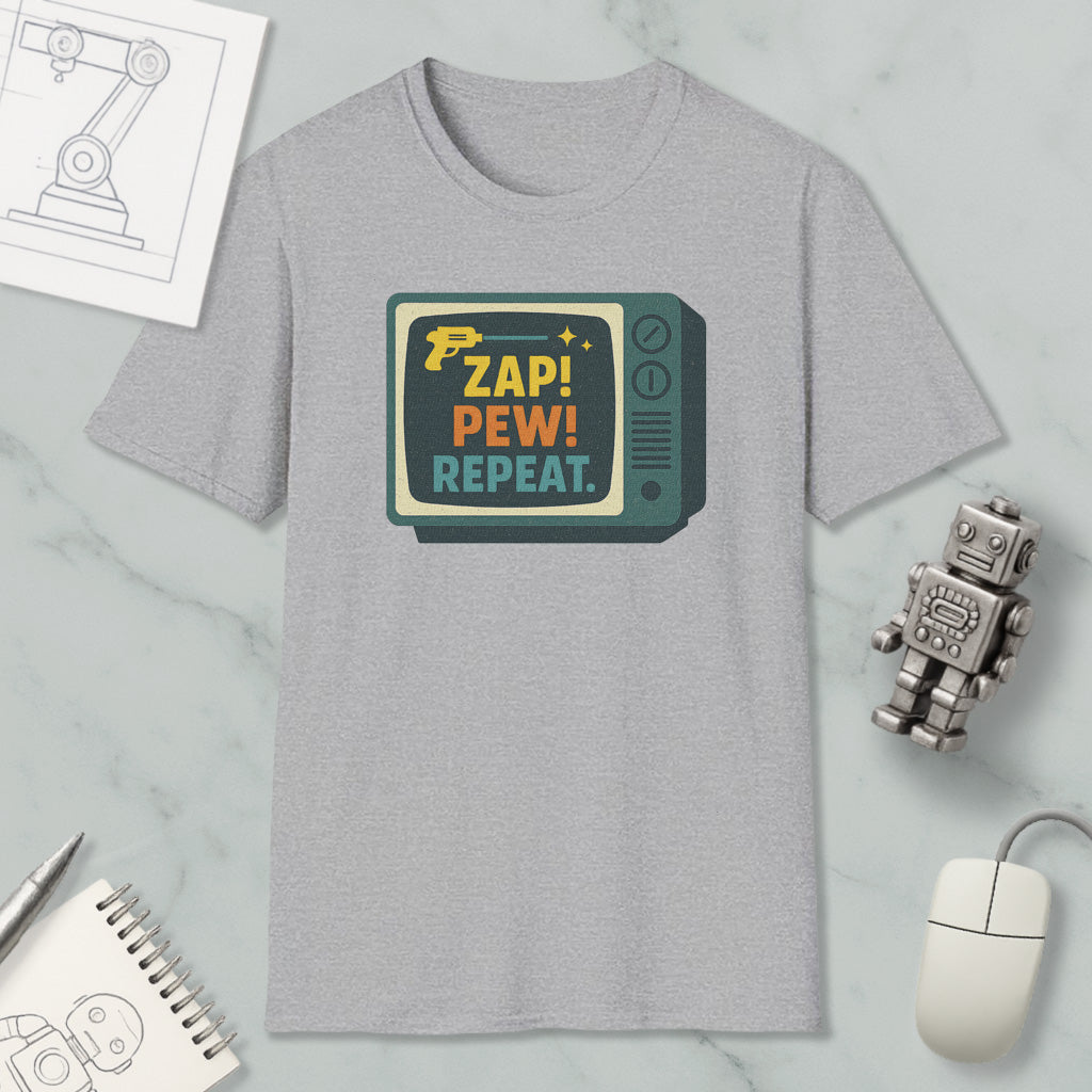 a gray t-shirt with a retro-style graphic design, a computer mouse, a pen, a notebook, and a small robot on a marble surface.