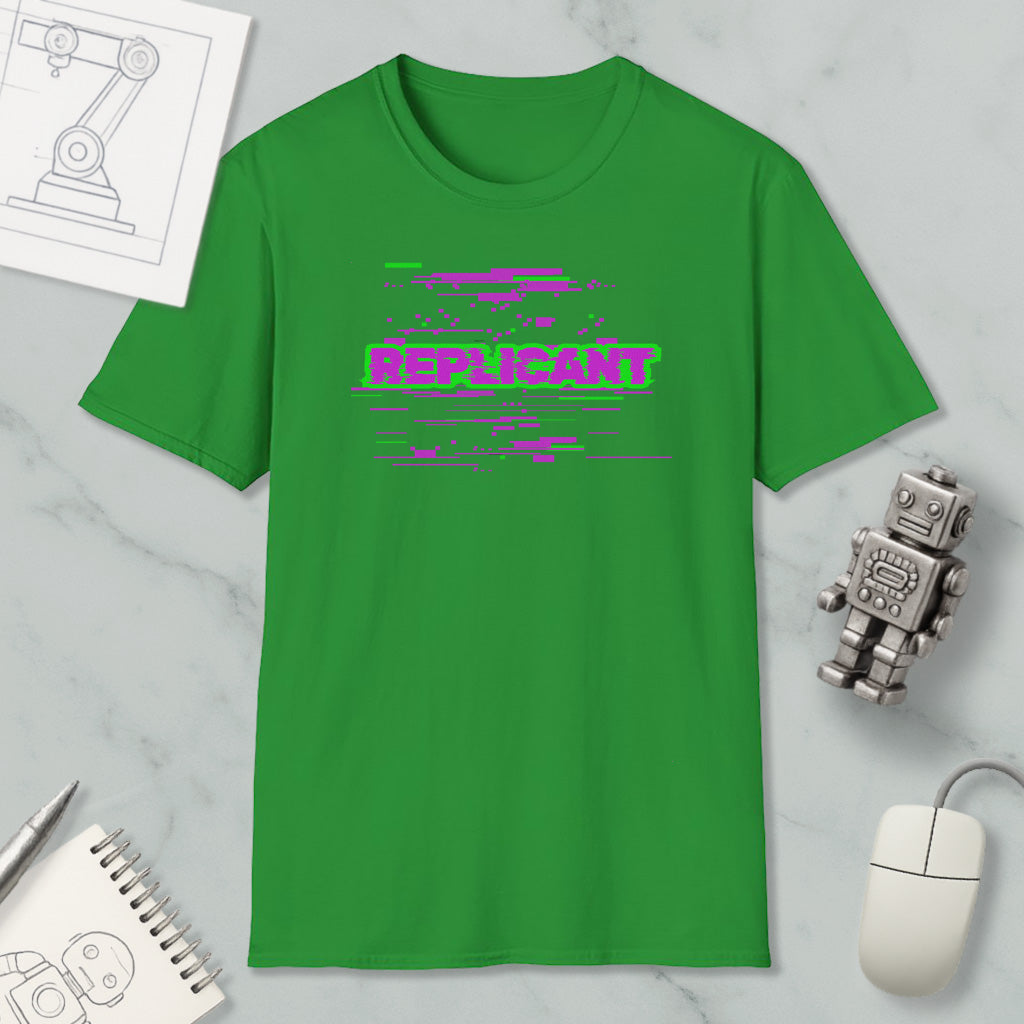a green t-shirt with a pink and purple graphic design, along with a computer mouse, a notebook, and a small robot figurine.