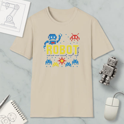 a beige t-shirt with a robot graphic and pixel art, along with a computer mouse, a notebook, and a small robot figurine.