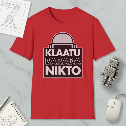 a red t-shirt with a graphic design, a computer mouse, a notebook, and a small robot figurine.