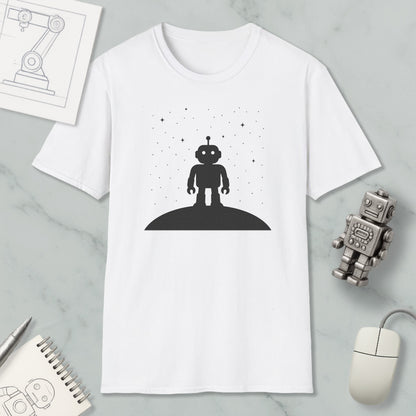 a white t-shirt with a black silhouette of a robot standing on a hill, surrounded by stars, and a small robot figurine is placed next to it.