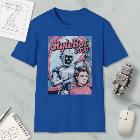 a blue t-shirt with a graphic design depicting a robot hairdresser styling a woman's hair. The t-shirt is placed on a marble surface, surrounded by various objects such as a computer mouse, a notebook, and a toy robot.