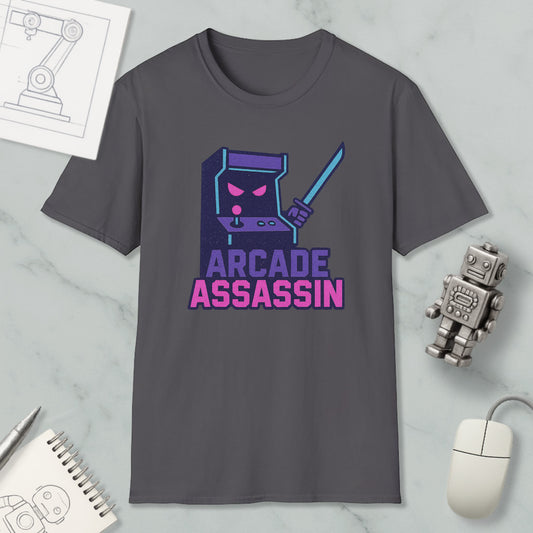 a gray t-shirt with a graphic design depicting a arcade game character and the text "ARCADE ASSASSIN" printed on it. The t-shirt is placed on a marble surface, surrounded by various objects such as a computer mouse, a pen, and a notebook.