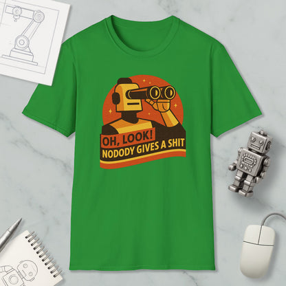 a green t-shirt with a graphic design depicting a robot character and the text "OH, LOOK! NODODY GIVES A SHIT" printed on it. The t-shirt is displayed on a marble surface, along with a computer mouse, a pen, and a notebook.