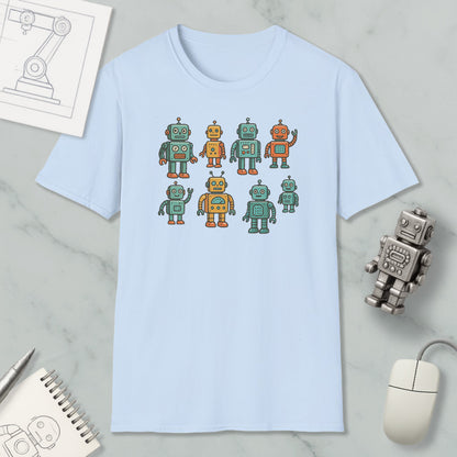 a light blue t-shirt with a graphic design of eight colorful robots, including four larger ones and four smaller ones, arranged in a square pattern. The t-shirt is placed on a marble surface, along with a computer mouse, a spiral notebook, and a small robot figurine.