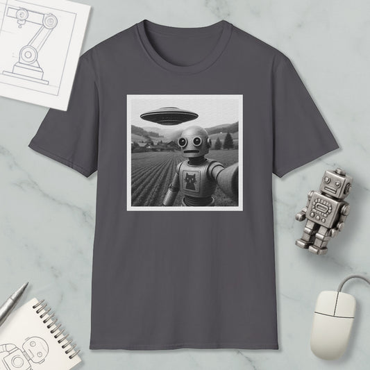 a gray t-shirt with a black and white photograph of a robot standing in a field, with a large spaceship flying above it. The t-shirt is displayed on a marble surface, along with a computer mouse, a notebook, and a small robot figurine.