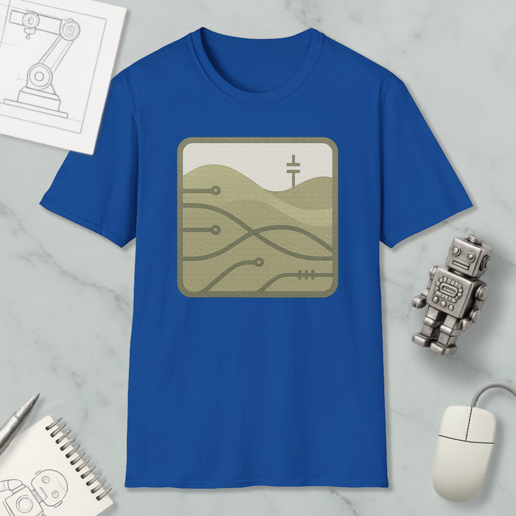 a blue t-shirt with a graphic design, a computer mouse, a notebook, and a small robot on a marble surface.