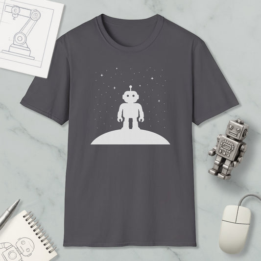 a gray t-shirt with a white robot standing on a planet, surrounded by a starry night sky. The t-shirt is placed on a marble surface, with a computer mouse, a notebook, and a robot figurine nearby.