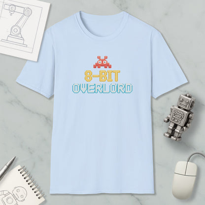 a light blue t-shirt with the text "8-BIT OVERLORD" printed on it, along with a small robot figure. The t-shirt is placed on a marble surface, and there are various objects such as a computer mouse, a spiral notebook, and a sketch of a robot figure nearby.