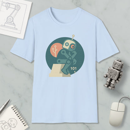 a light blue t-shirt with a graphic design of a robot, a computer mouse, and a notebook, all placed on a marble surface.