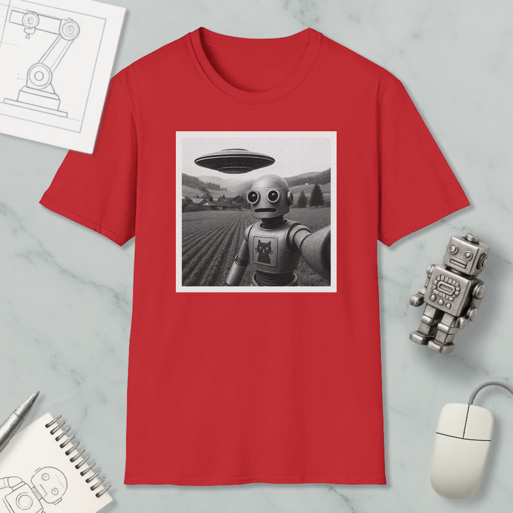 a red t-shirt with a black and white photograph of a robot and an alien spacecraft, along with various objects such as a notebook, a mouse, and a pen.